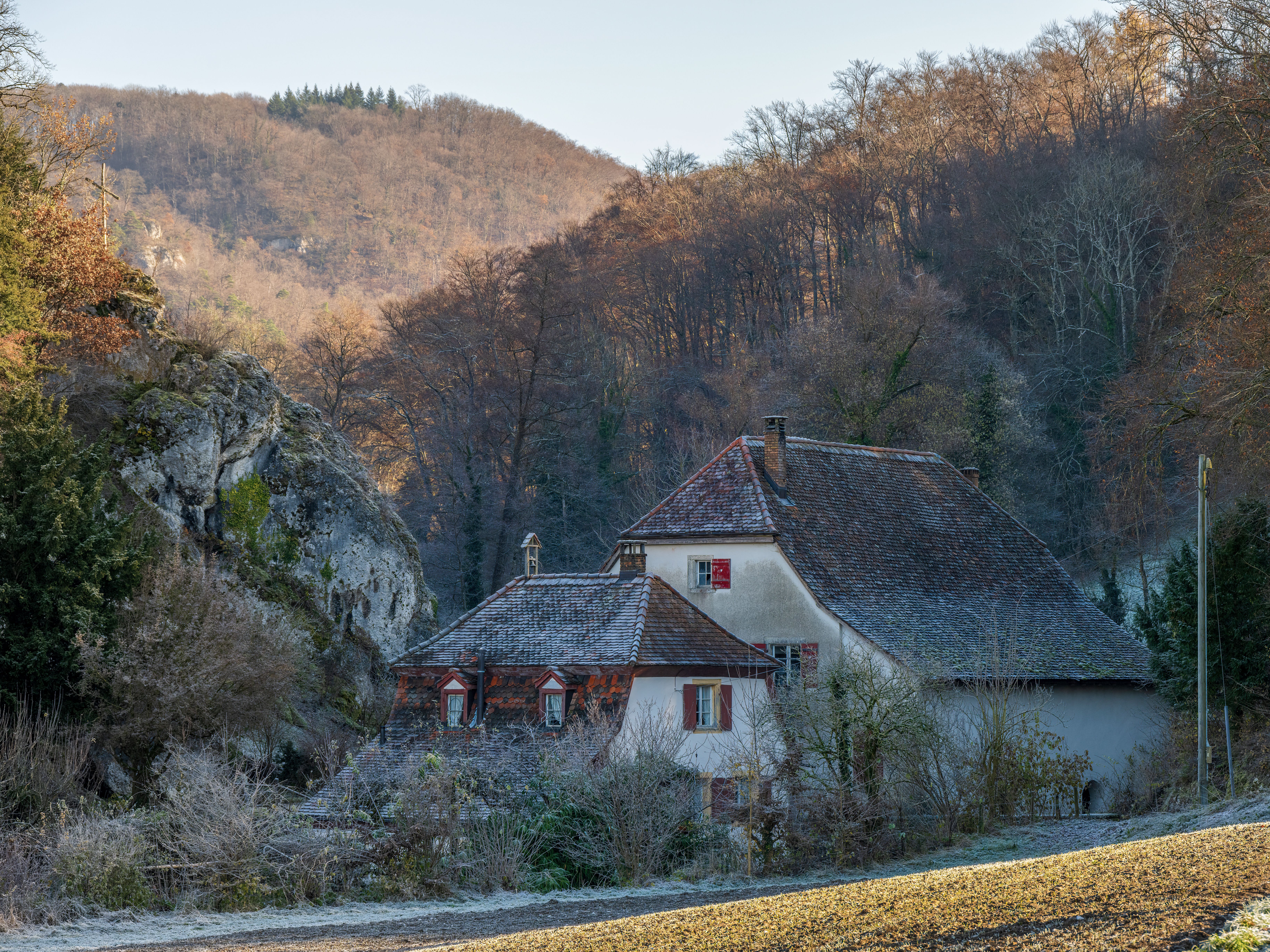 Maison pittoresque nichée au milieu des bois d'automne et d'un paysage rocheux.