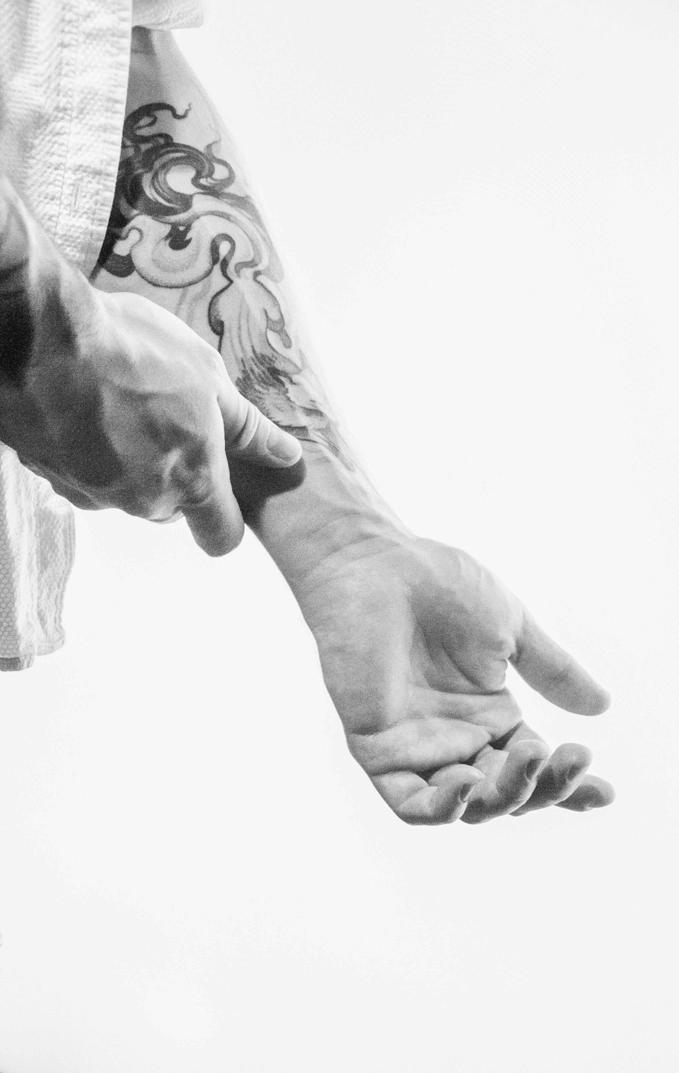 Close-up of a tattooed arm with rolled-up sleeve in a minimalist black and white style.