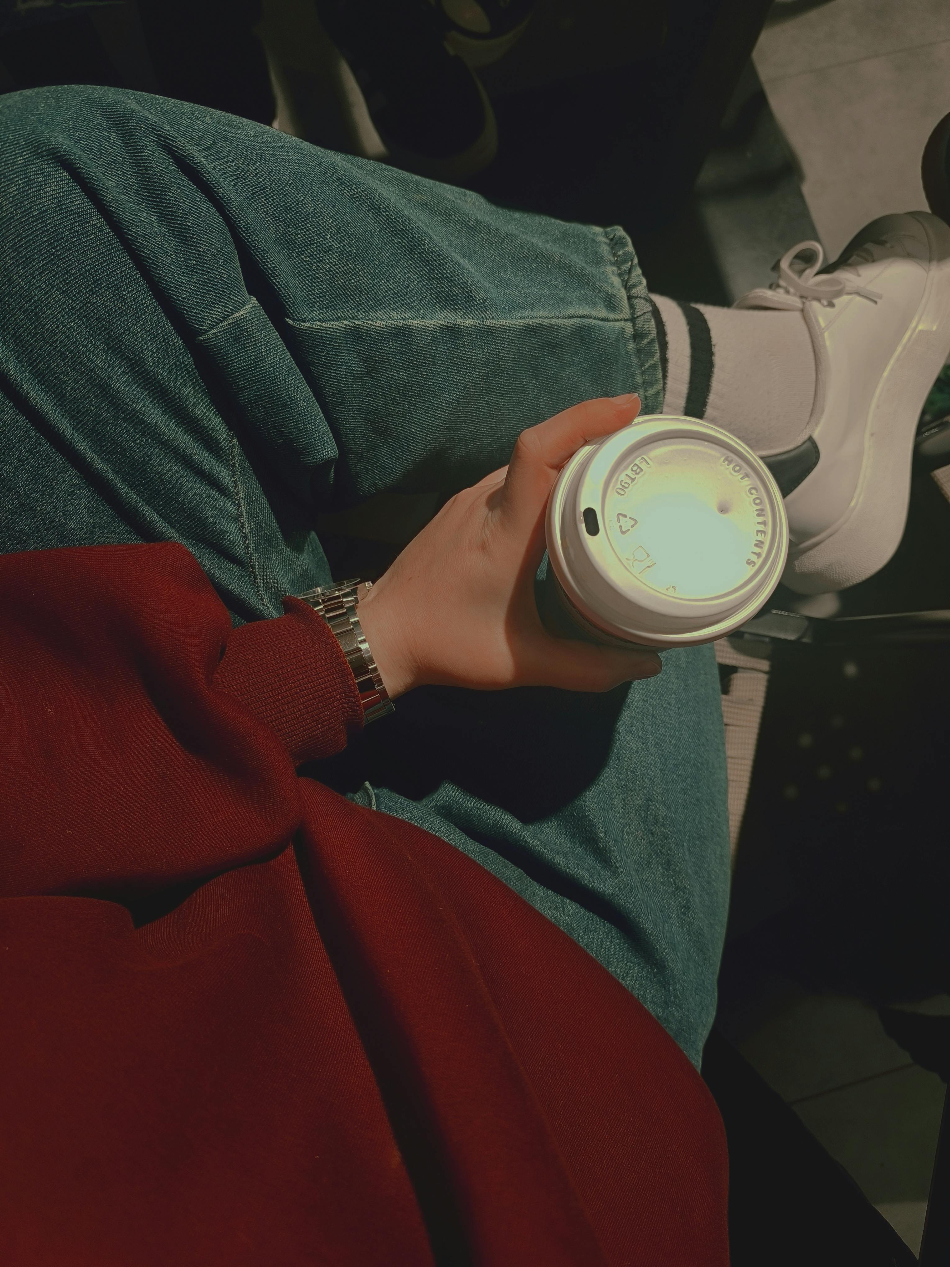 Casual scene with person holding coffee cup in comfortable outfit.