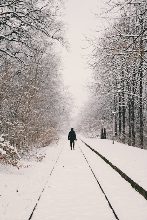 Man Walking on Rail Covered With Sbow