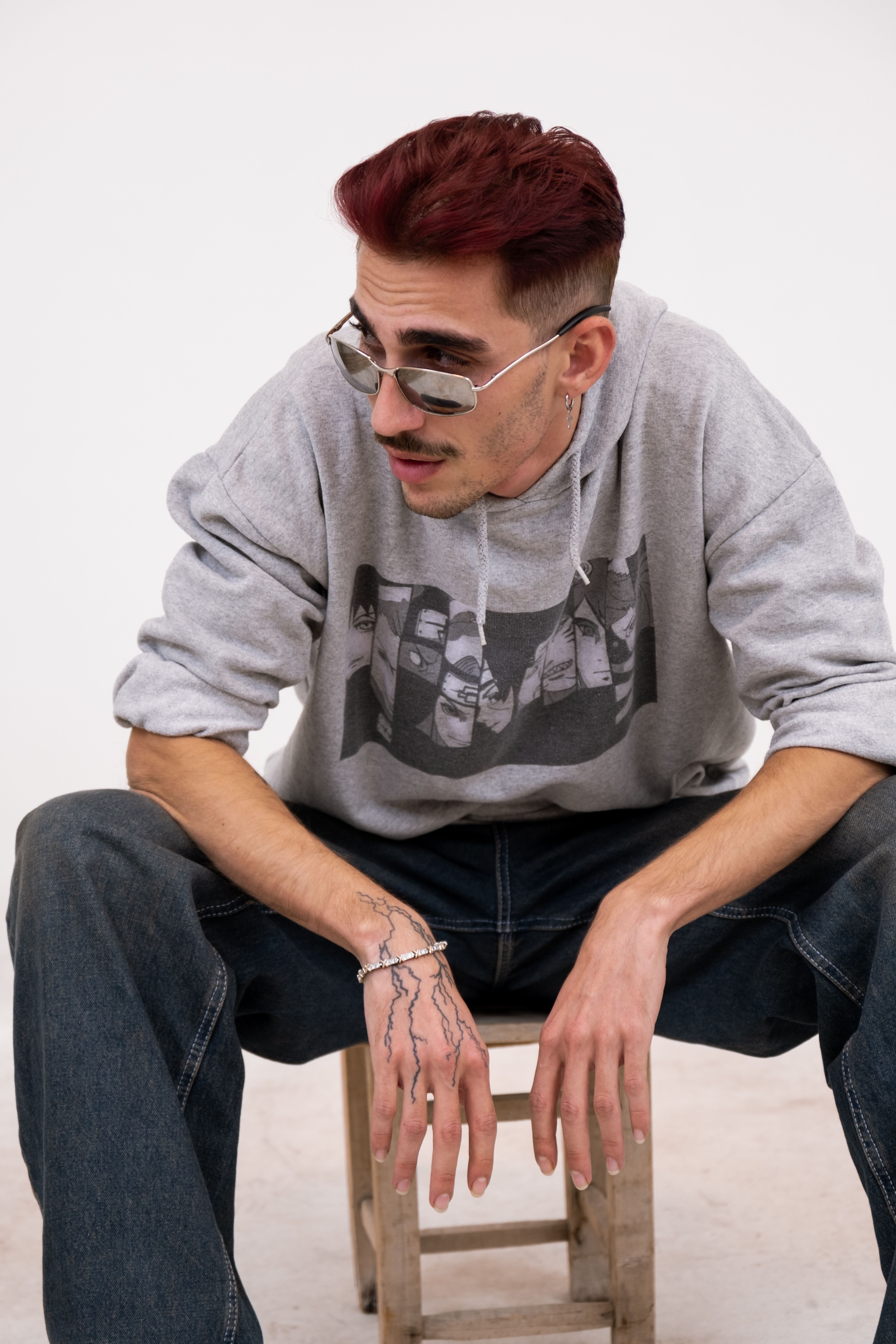 Stylish young man with sunglasses wearing a graphic hoodie. Urban fashion indoors.