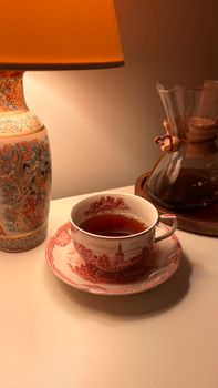 A serene scene of a tea cup, vintage lamp, and Chemex for a warm evening vibe.