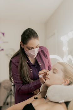 Professional cosmetologist applying makeup to a client in a modern salon.