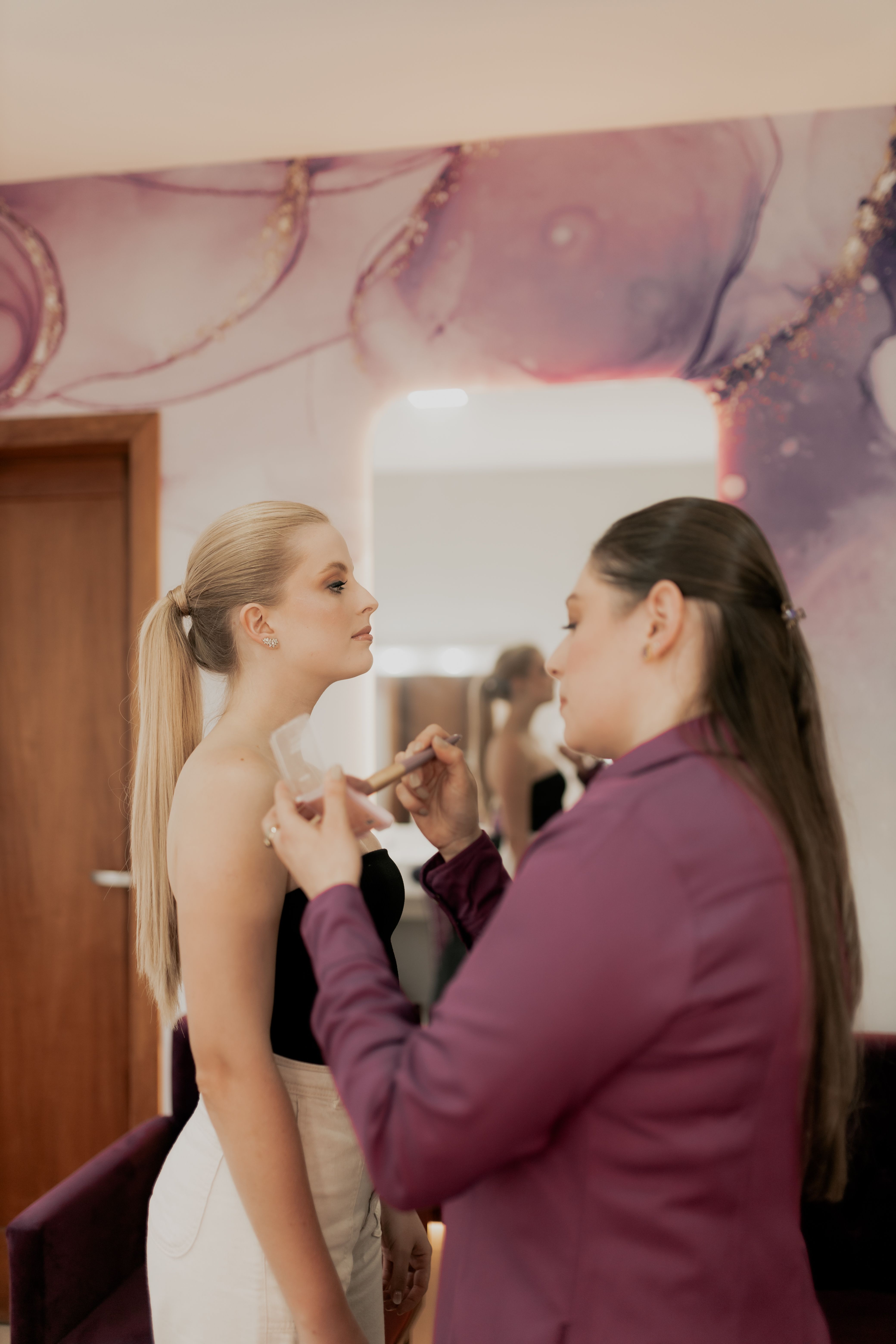 Stylist assists model with final touches in dressing room.