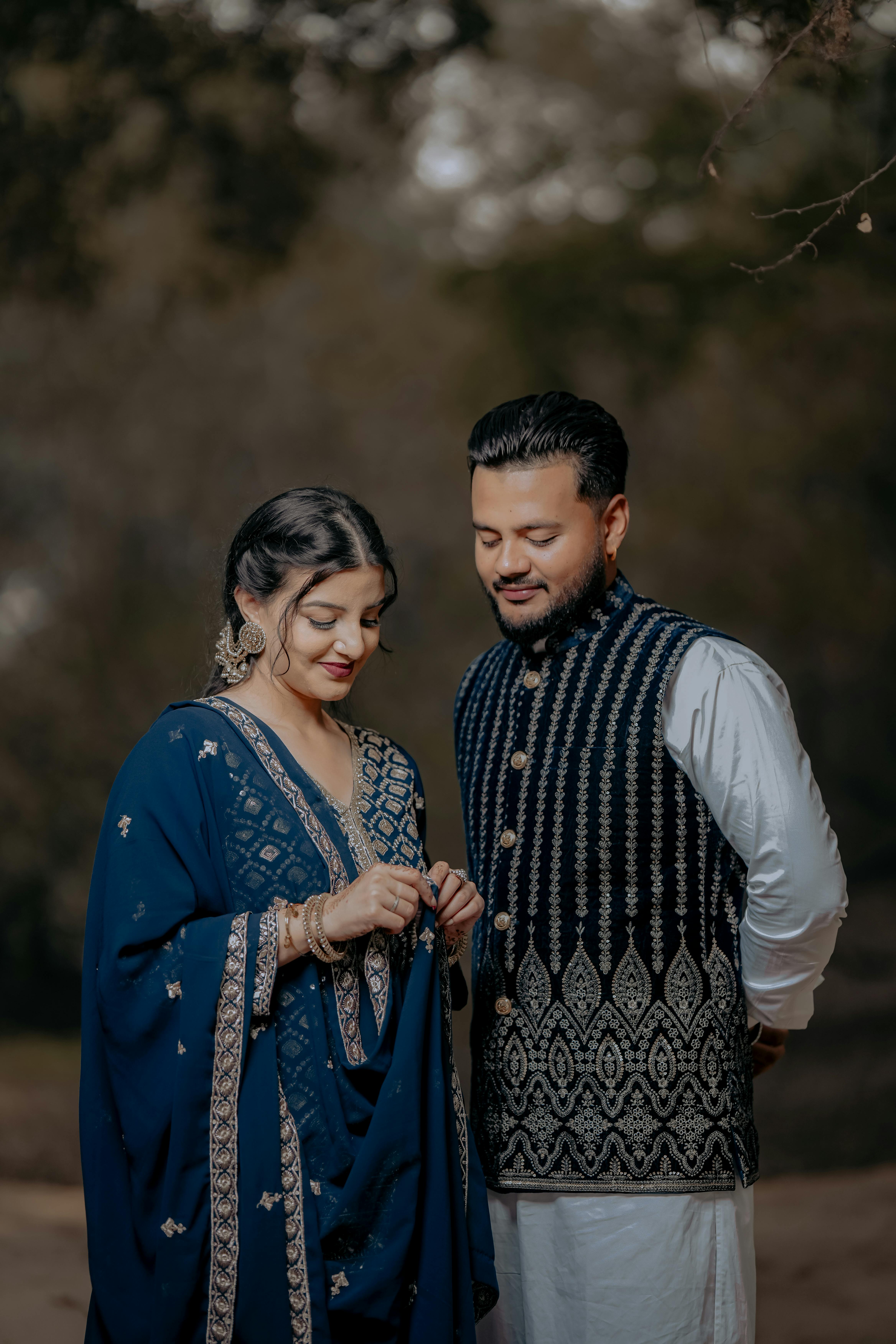 A couple dressed in traditional Indian clothing, captured outdoors in natural light.