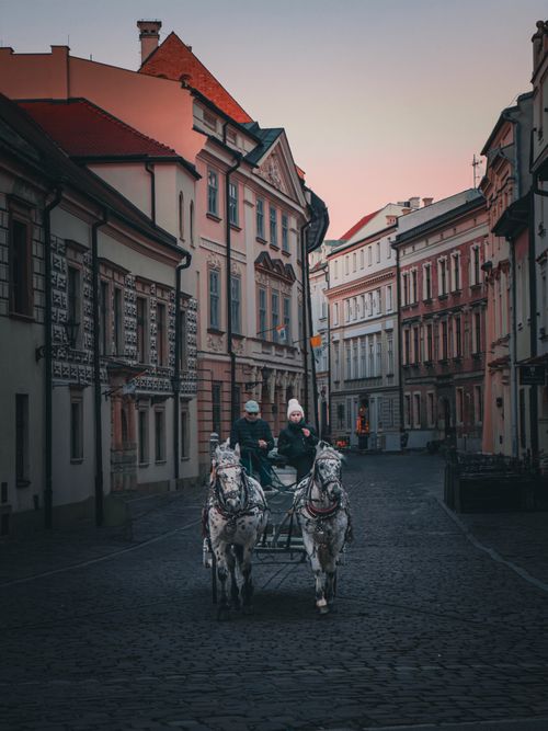 Free A horse-drawn carriage navigates a cobblestone street in Kraków, Poland at dusk. Stock Photo