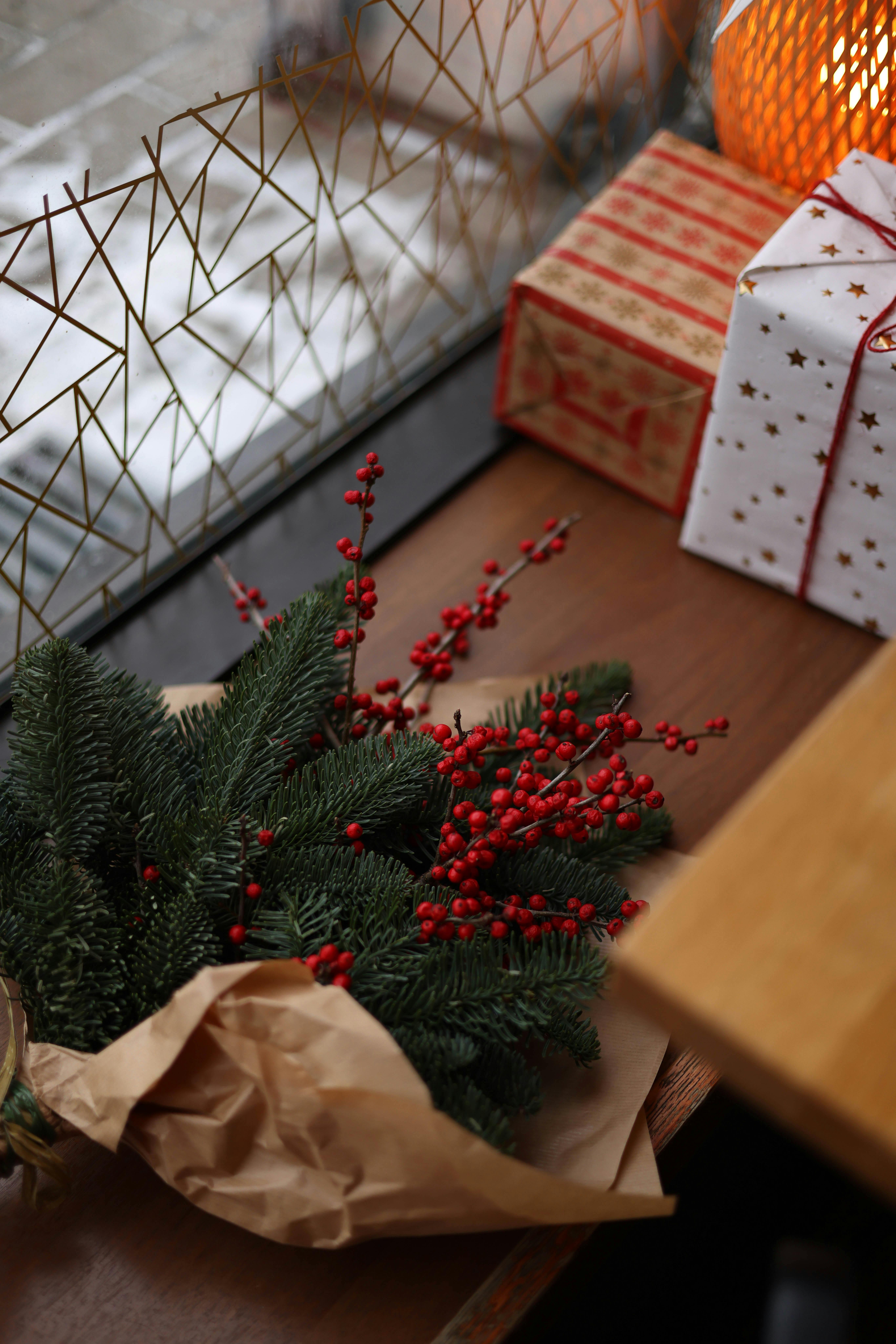 Christmas gifts with red berries and pine branches set in a cozy corner.