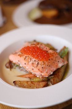 Delicious gourmet salmon with vibrant roe, served with roasted vegetables.