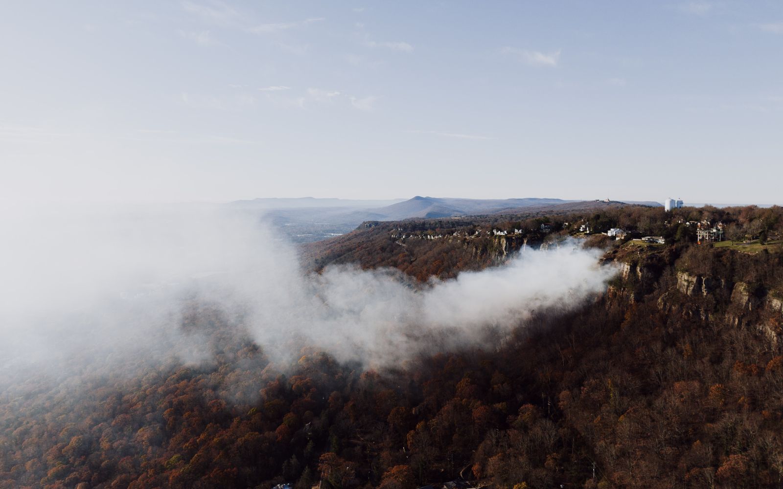 Aerial view of smoke billowing over forested hills and a mountain ridge