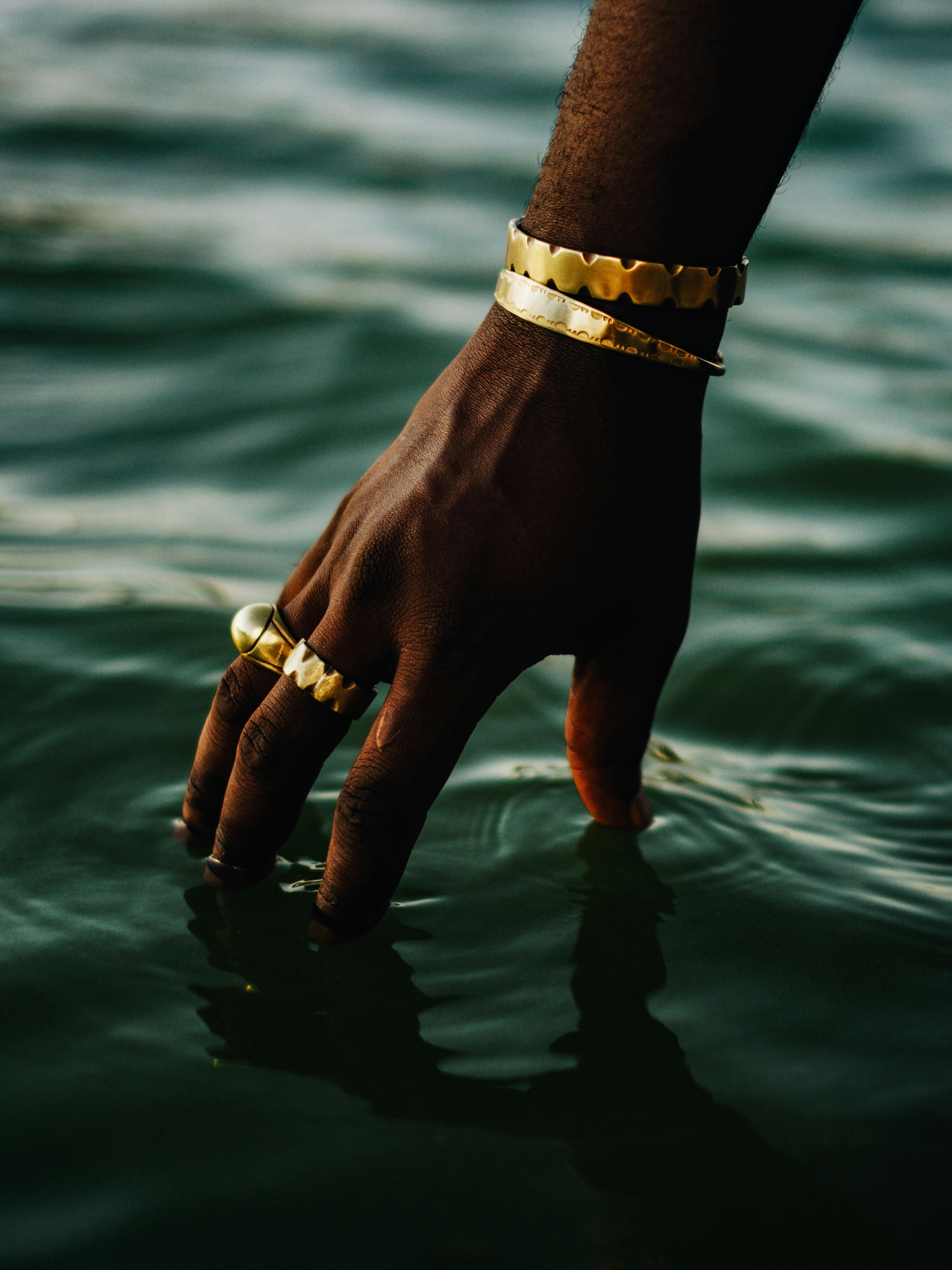 elegant hand with gold jewelry touching water