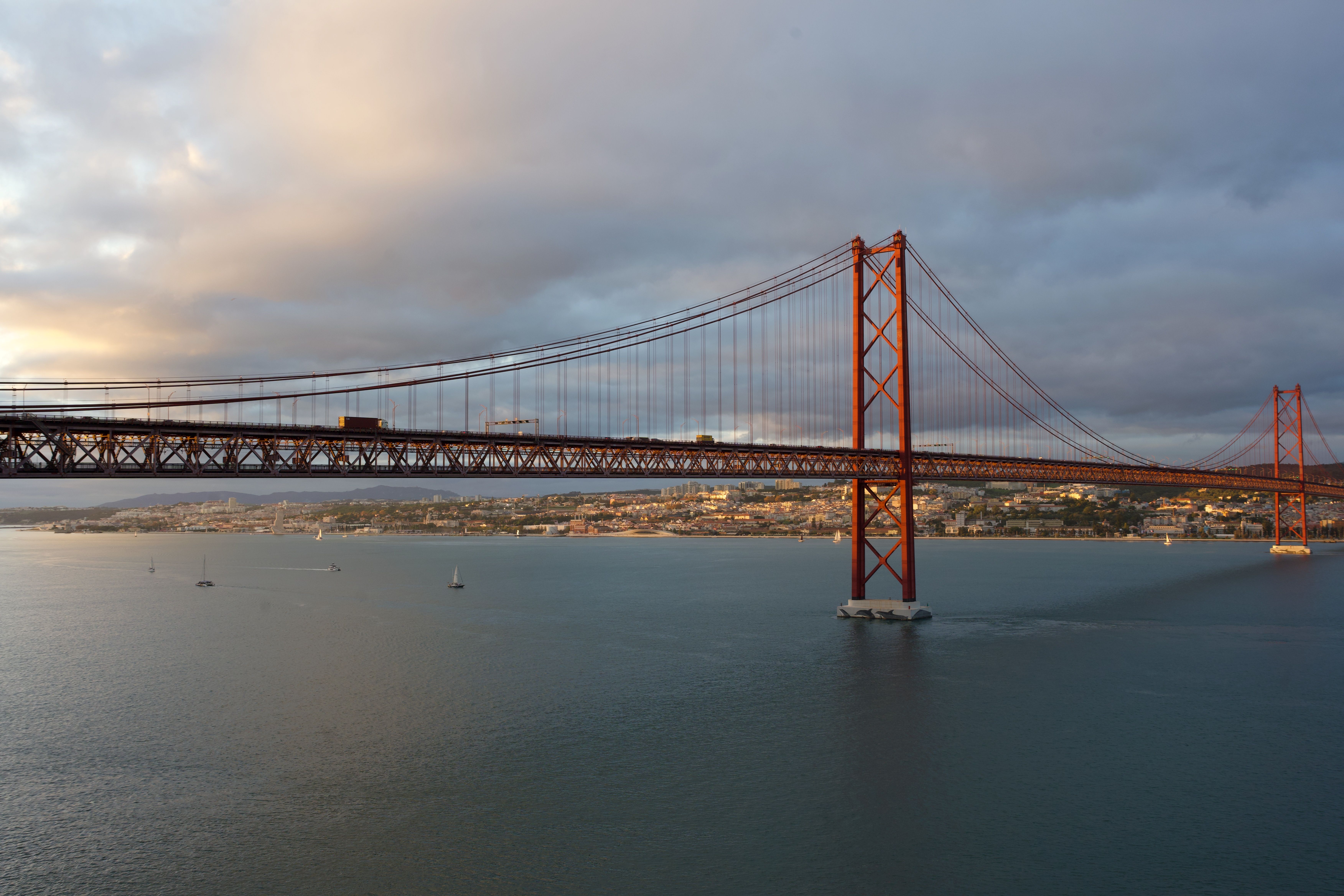 Breathtaking sunset view of Lisbon's famous bridge over calm waters. - Monsanto