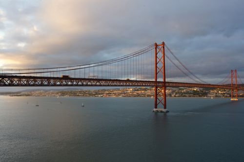 Free Breathtaking sunset view of Lisbon's famous bridge over calm waters. Stock Photo