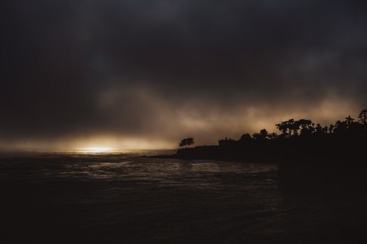 Silhouette of trees against a dramatic sunset at Pismo Beach, creating a moody seascape.