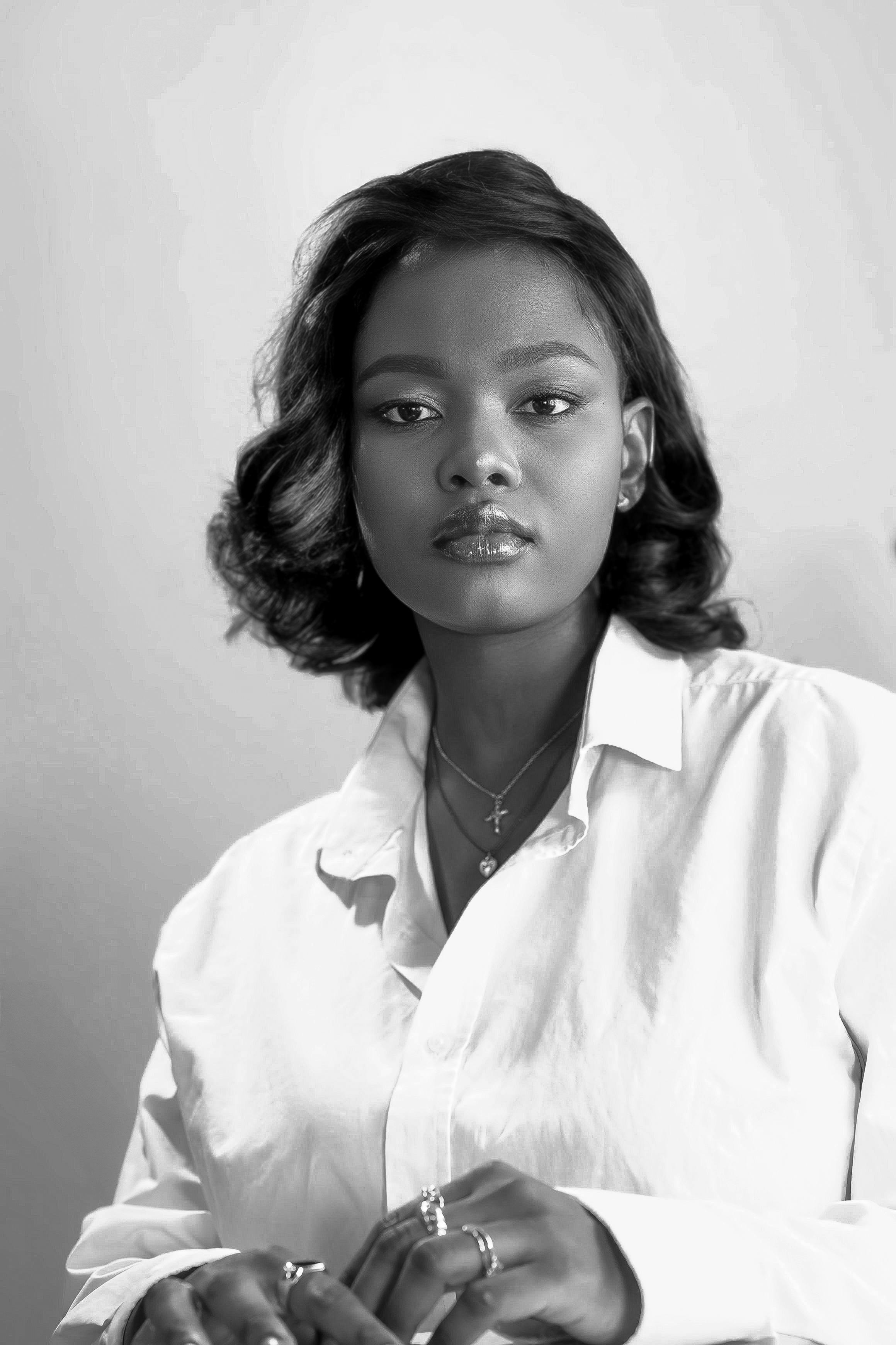 Striking black and white portrait of a woman in a white blouse, capturing elegance and grace.