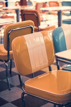 Colorful vintage-style diner chairs in a retro cafe with checkered flooring.