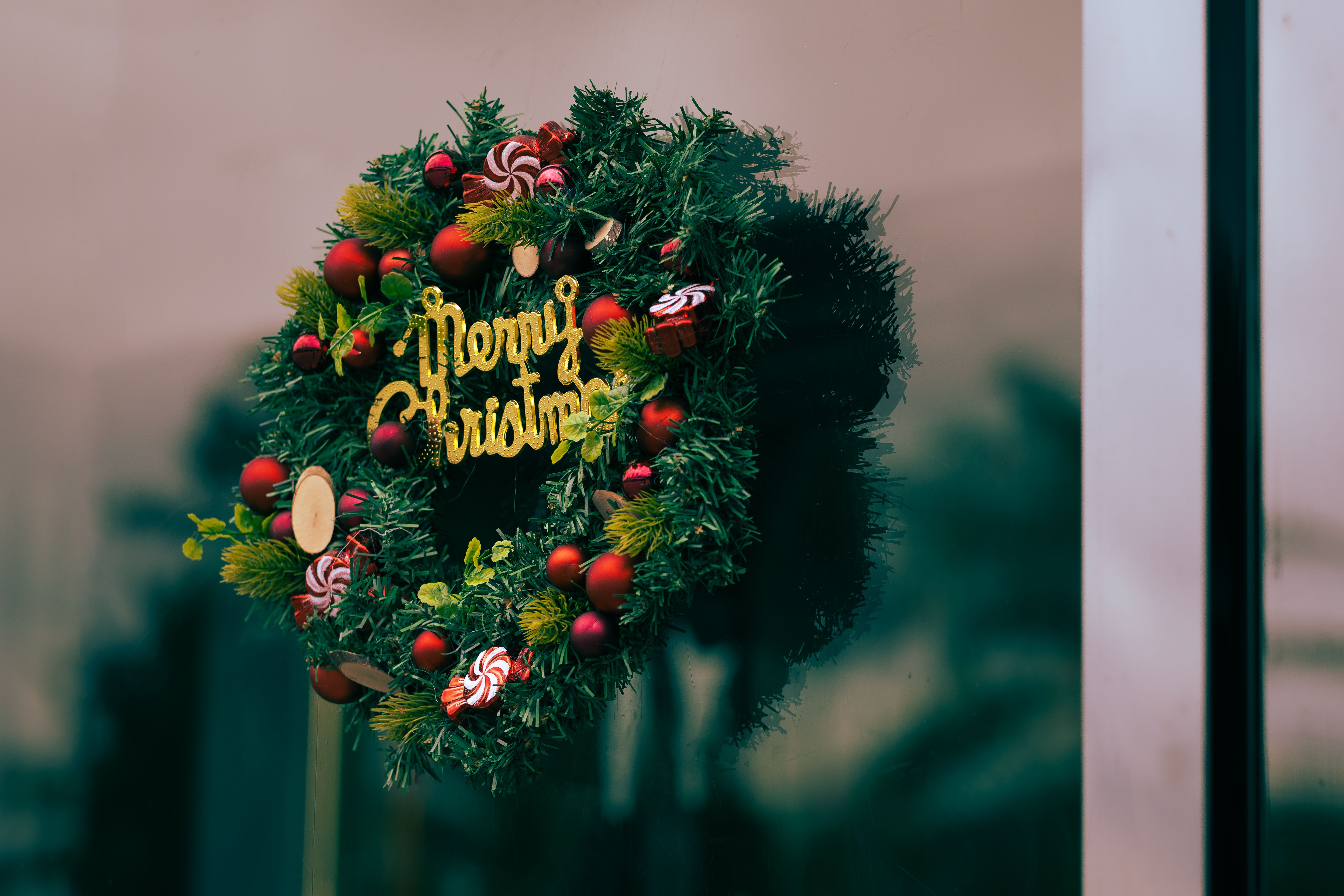 Vibrant Christmas wreath with decorations and 'Merry Christmas' text on a glass door.