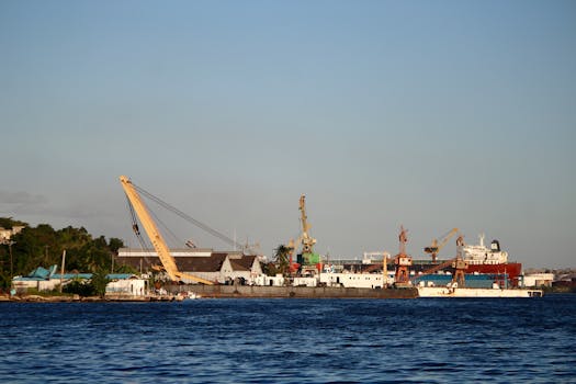 Shipyard scene featuring cranes and ships by the water on a clear day.