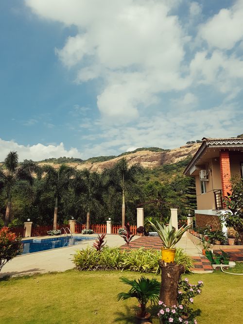 Free Outdoor pool area with lush greenery and mountain backdrop under a blue sky. Stock Photo