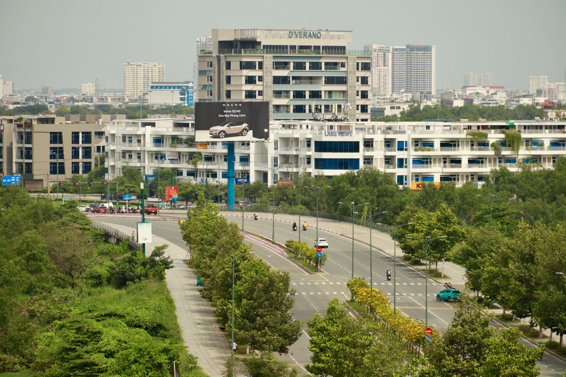 A cityscape view of modern buildings and a curved road surrounded by greenery.