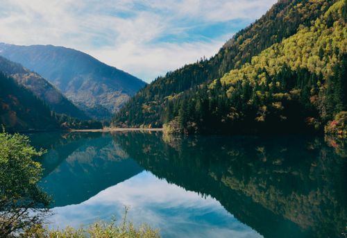 Free A serene lake reflecting scenic mountains and lush fall foliage. Stock Photo