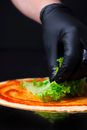 Person With Gloves Putting Lettuce on Pizza