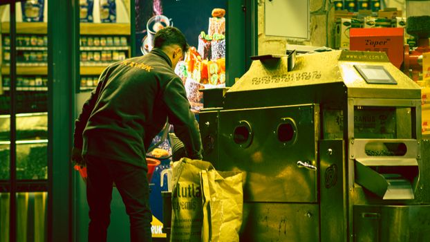 An adult male working next to a large industrial machine indoors. Captured with a unique color tone.