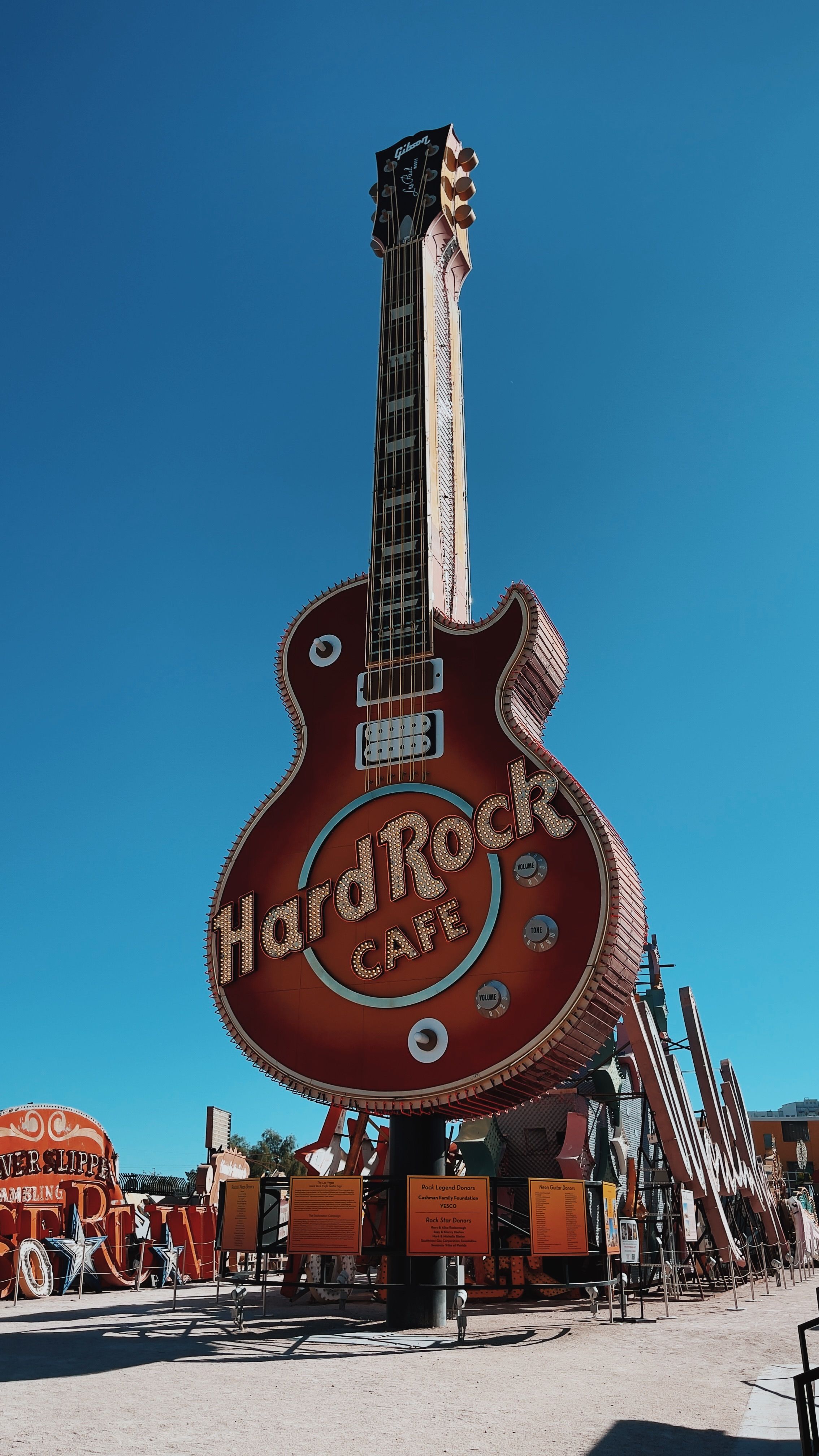 Large Hard Rock Cafe guitar sign in outdoor neon museum on a clear day.