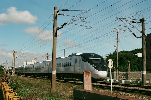 High-speed train moving through Taiwan's scenic countryside on a sunny day.