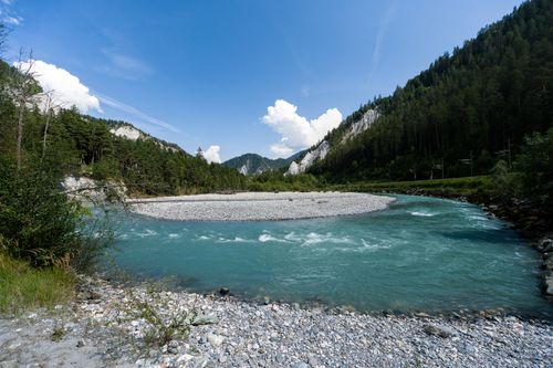 Free Crystal clear alpine river winding through scenic Swiss landscape under a bright blue sky. Stock Photo