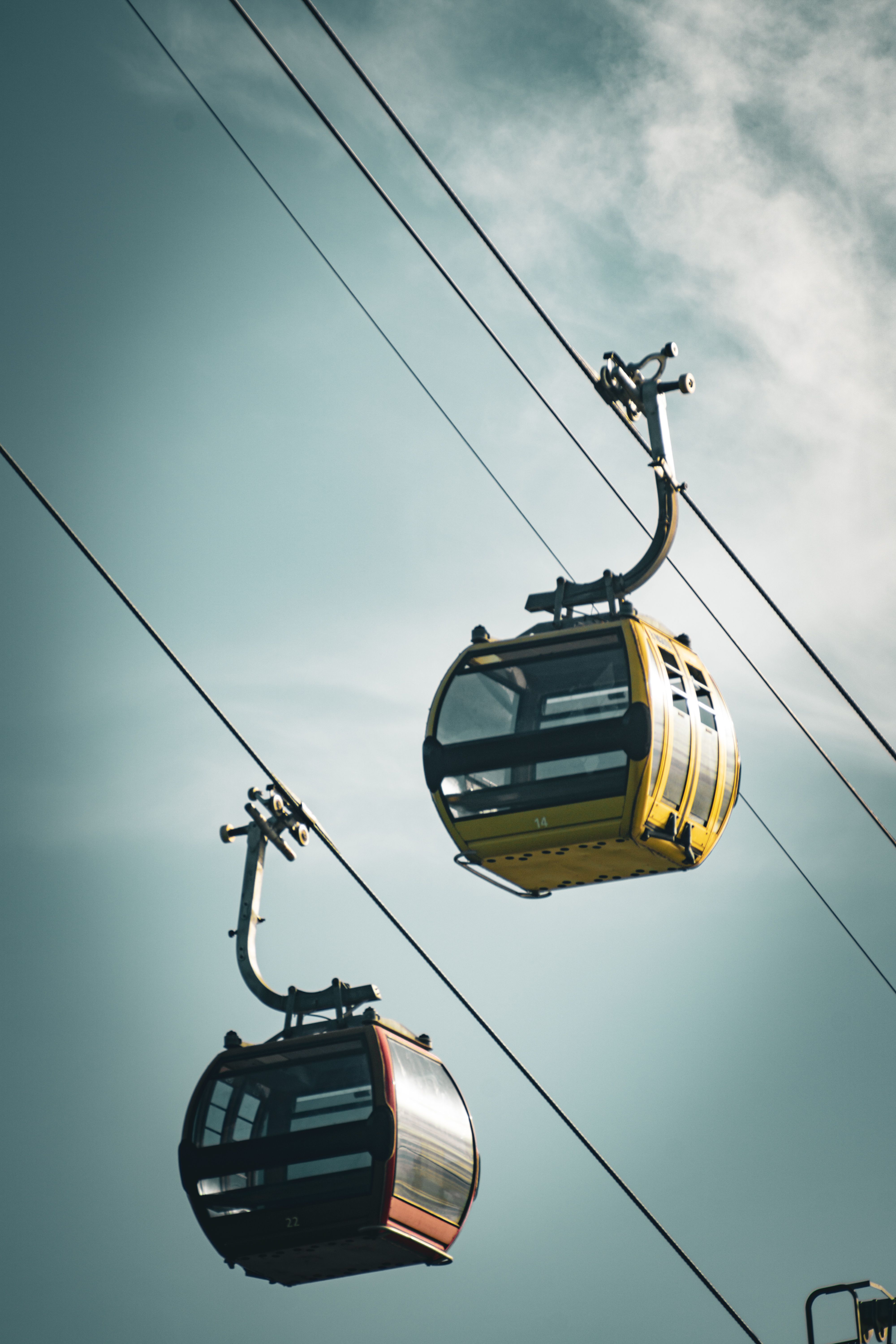 Two colorful cable cars suspended on wires against a clear blue sky, ideal for travel imagery.