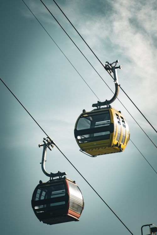 Free Two colorful cable cars suspended on wires against a clear blue sky, ideal for travel imagery. Stock Photo