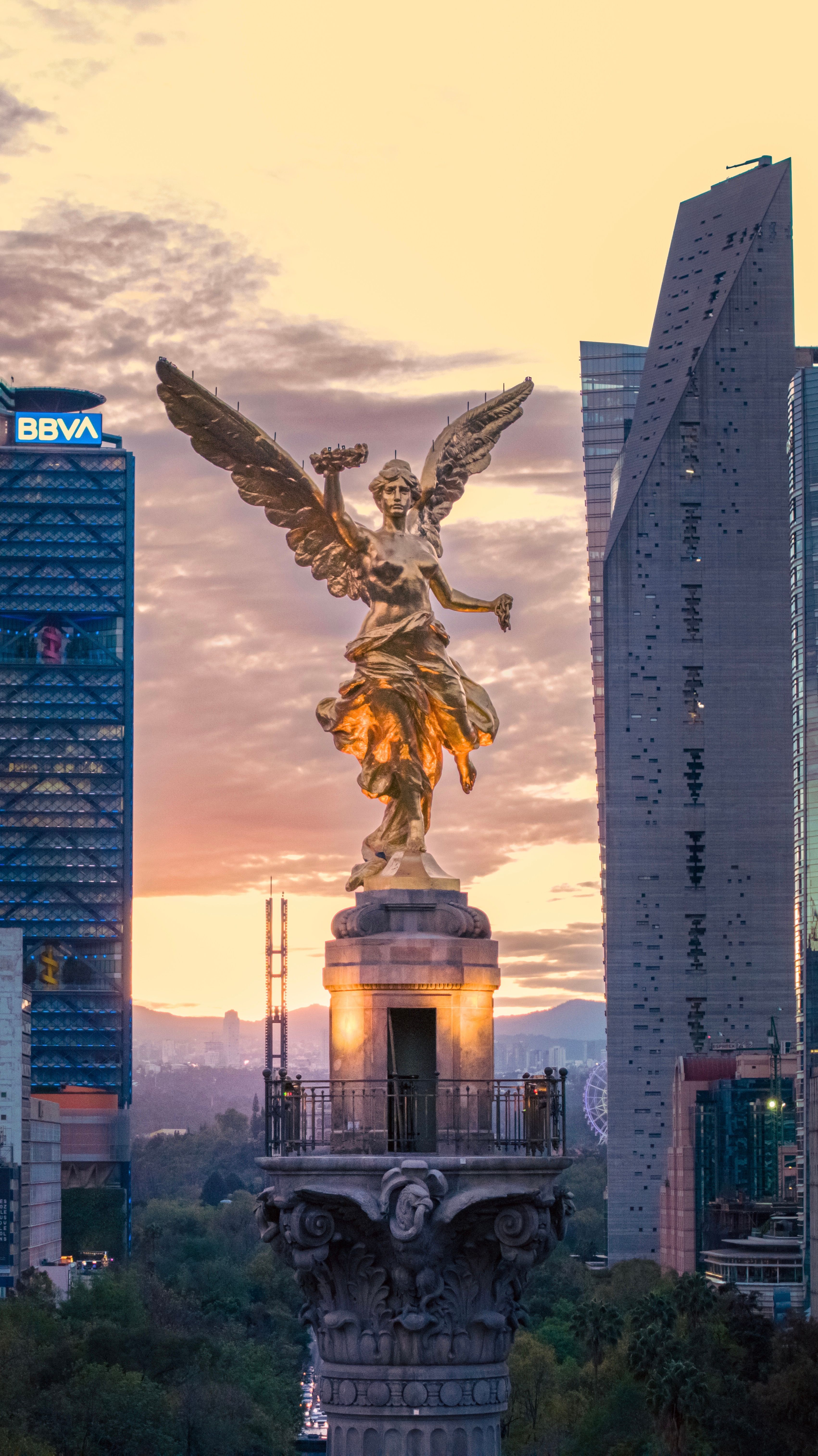 The Angel of Independence golden against the sunset, framed by towers