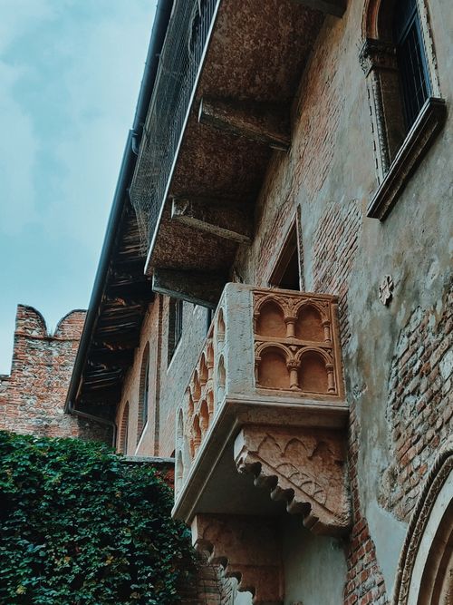 Free A low-angle view of an old stone balcony on a historic brick building exterior. Stock Photo
