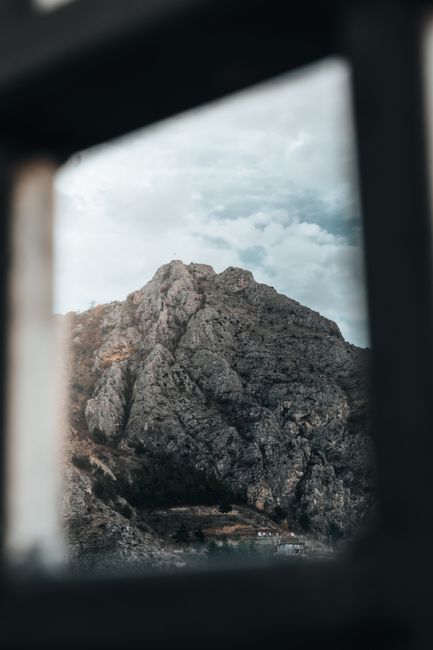 A breathtaking mountain landscape framed by a window, showcasing nature's rugged beauty.