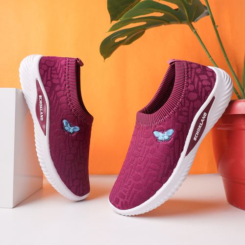 Free Elegant purple sneakers with butterfly embroidery on an orange backdrop, perfect for a vibrant lifestyle. Stock Photo