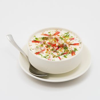 A bowl of creamy Indian raita garnished with fresh vegetables and spices, perfect for a side dish.