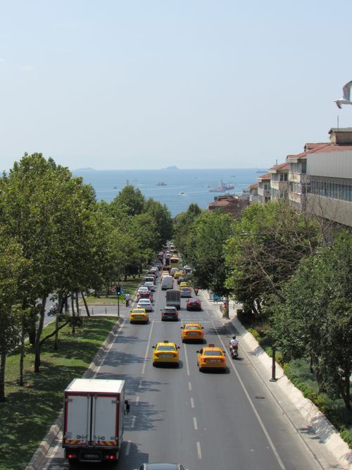 Free A bustling Istanbul street lined with trees, leading to the sea, under clear skies. Stock Photo