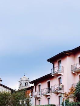 这座美丽的粉红色建筑，在晴朗的天空下拥有华丽的阳台，旁边还矗立着一座塔