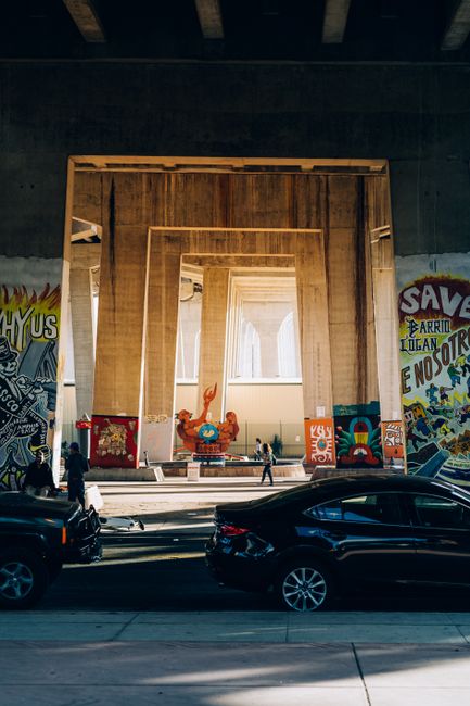 Street scene featuring vibrant graffiti on an underpass with passing cars and pedestrians.
