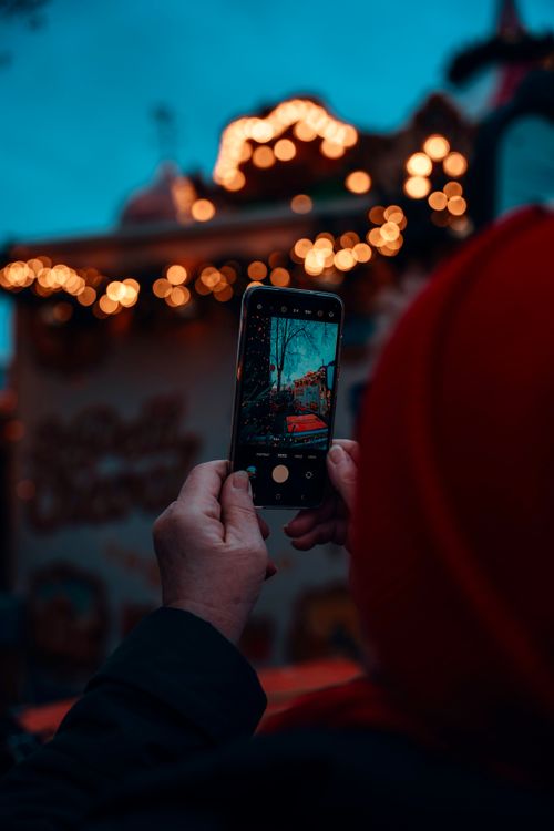 Free A person photographing Berlin's Christmas market ambiance with a smartphone during the festive season. Stock Photo