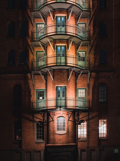 Free Illuminated brick warehouse façade with balconies in Hamburg's Speicherstadt at night. Stock Photo