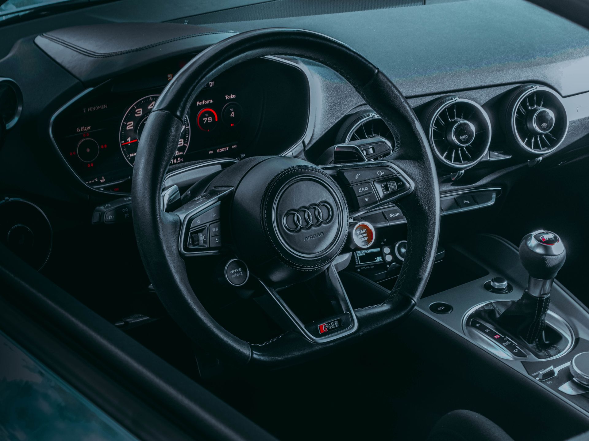 Close-up of an Audi car interior highlighting the steering wheel and dashboard.