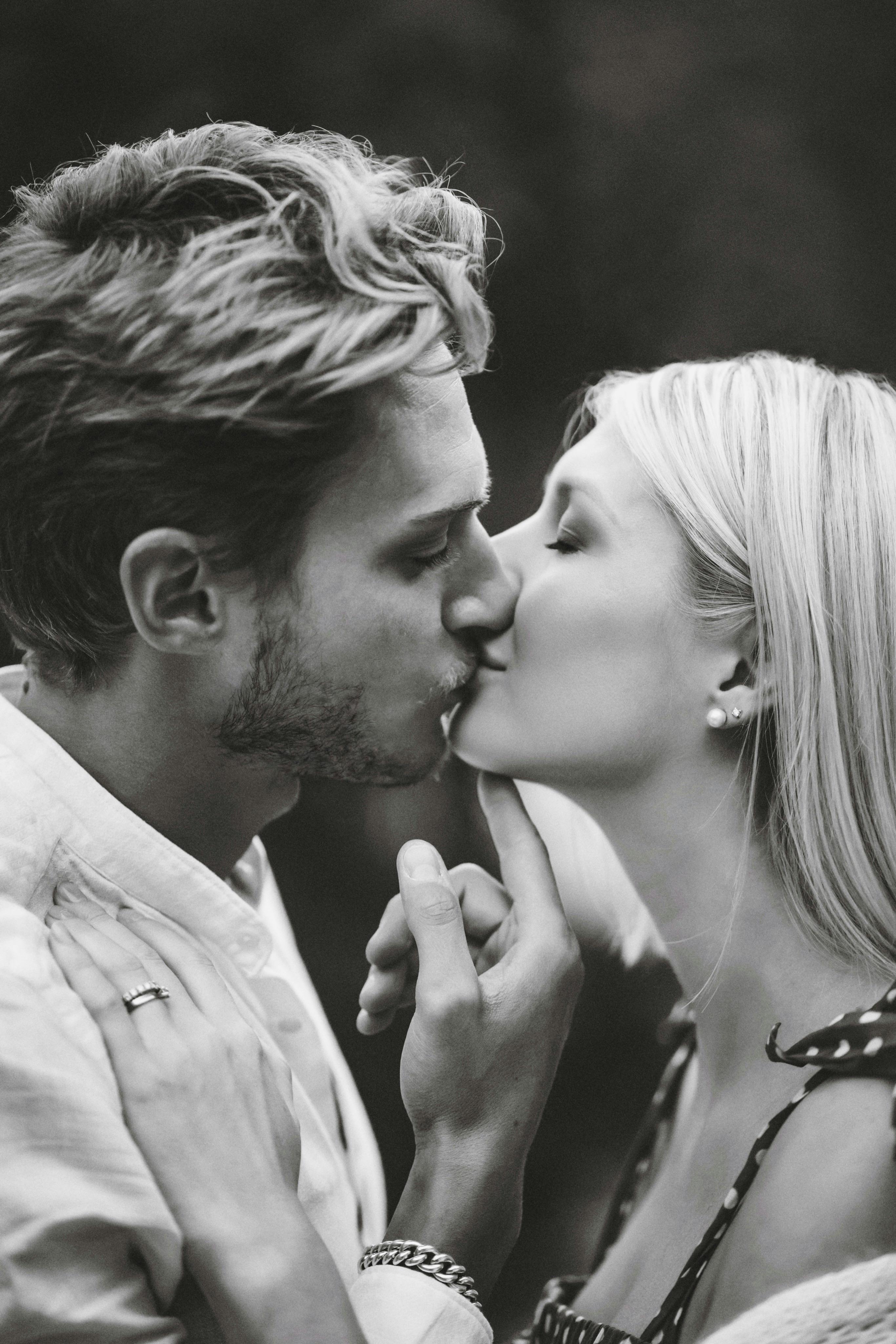A tender black and white portrait of a couple kissing, capturing romance and intimacy.