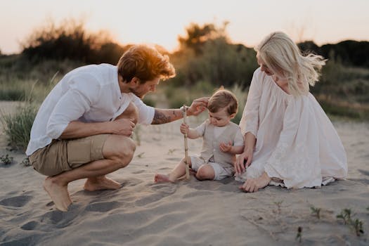 A family with a toddler enjoying a peaceful moment on a beach at sunset.