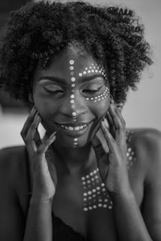 Black and white portrait of a woman with tribal face paint, expressing elegance and beauty.
