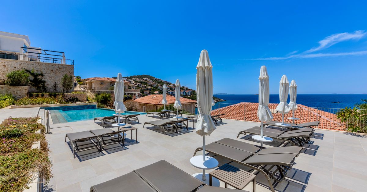 Relaxe na luxuosa piscina com espreguiçadeiras e guarda-sóis, com vista para o mar e a bela paisagem costeira.