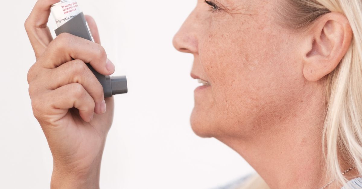 Middle-aged woman using an asthma inhaler to alleviate breathing difficulties. - Evidence evidence guide for NAC Respiratory Randomized Trial: What the Evidence Says