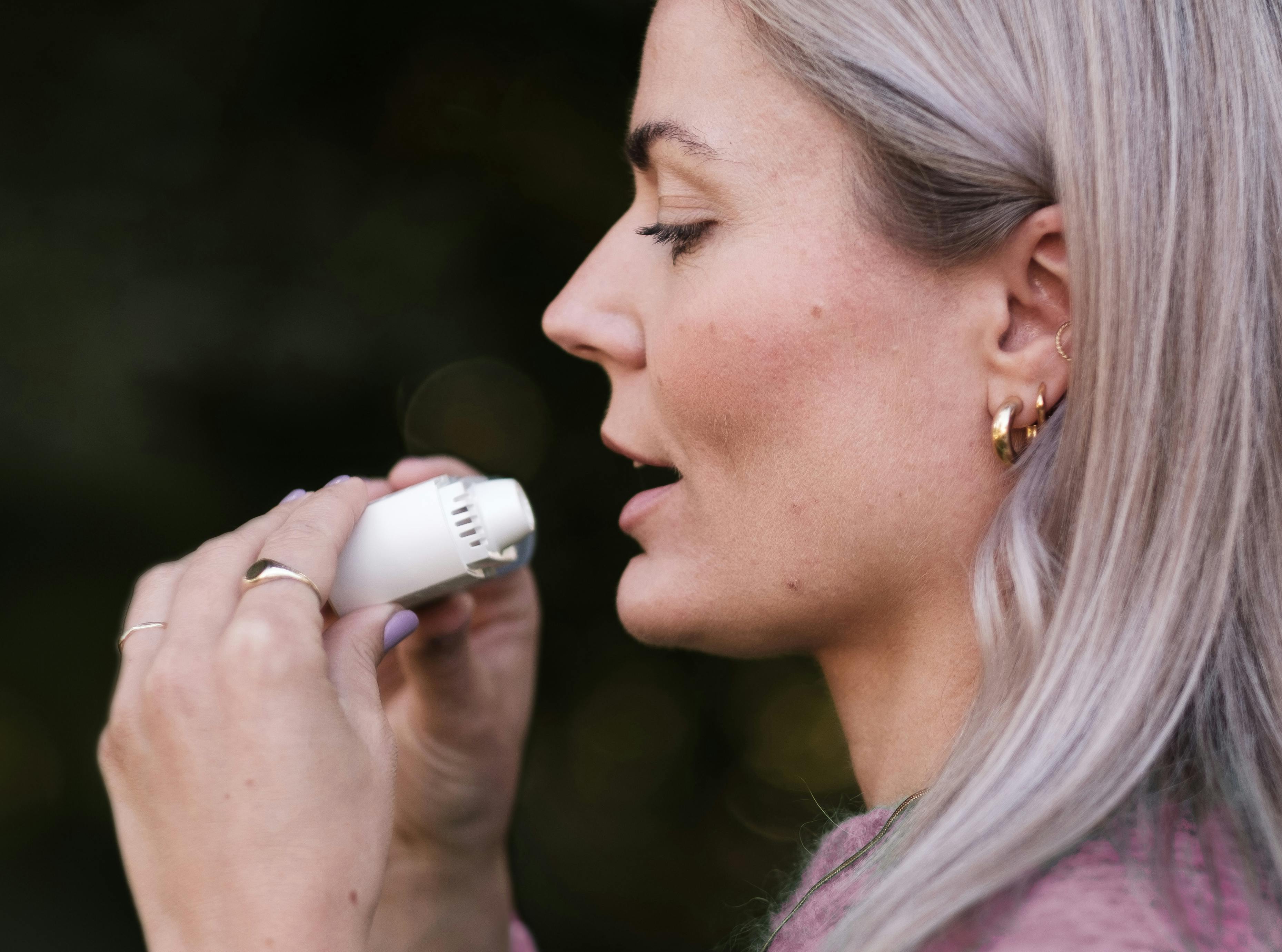 Woman Using Portable Personal Inhaler Device Outdoors · Free Stock Photo
