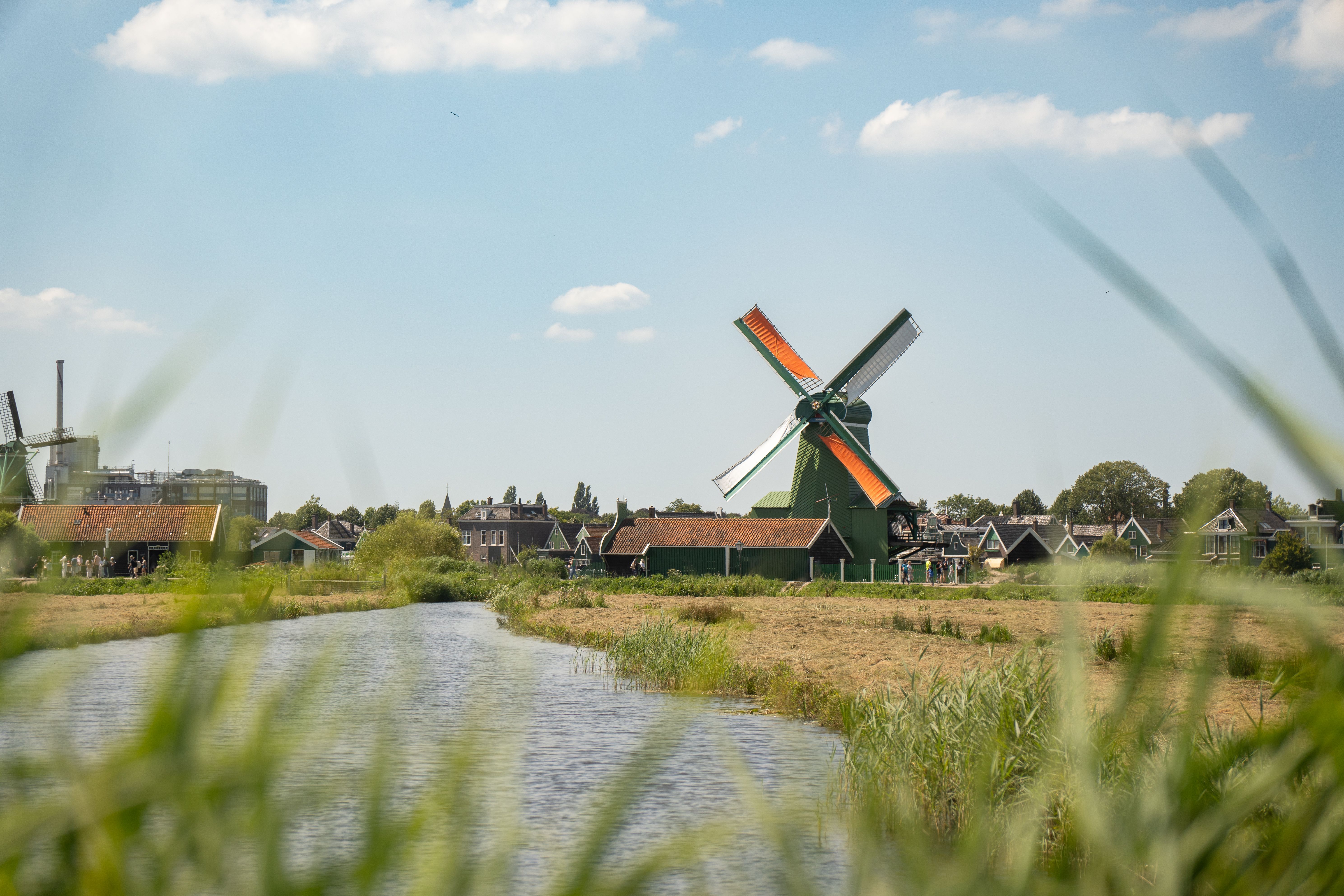 Scenic view of a traditional windmill near a river in Zaandam, Netherlands.