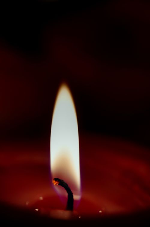 Free A close-up shot of a candle flame casting warm, soft light in darkness. Stock Photo